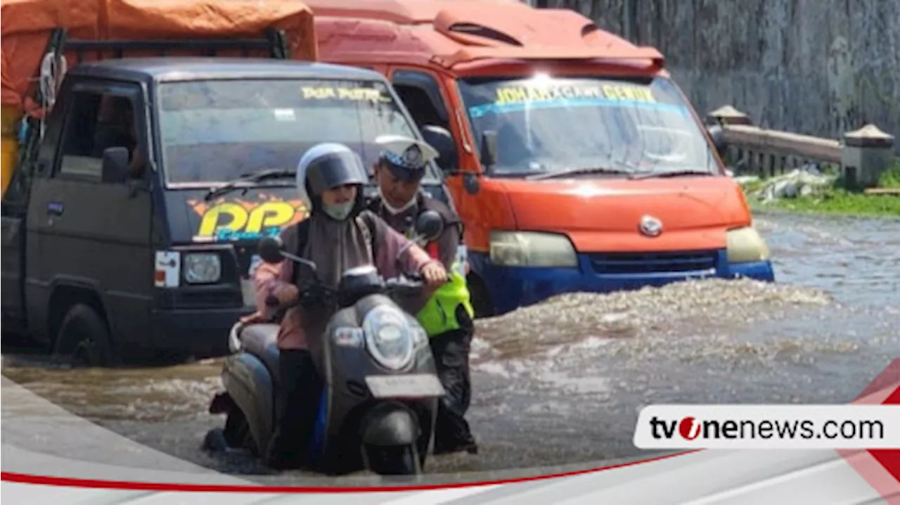 Police officers help motorcyclists affected by floods in Semarang