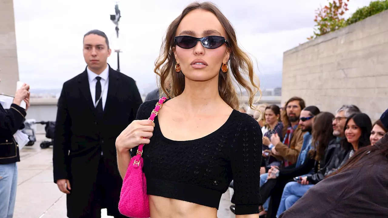 Lily-Rose Depp flaunts her washboard abs in a black crop top and pink mini skirt as she poses at the...