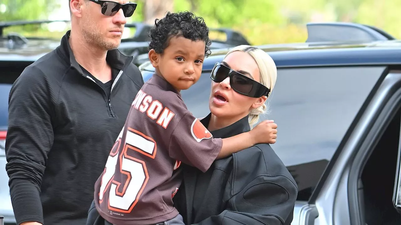 Kim Kardashian covers her curves in a baggy black outfit as she carries her son Psalm days before...