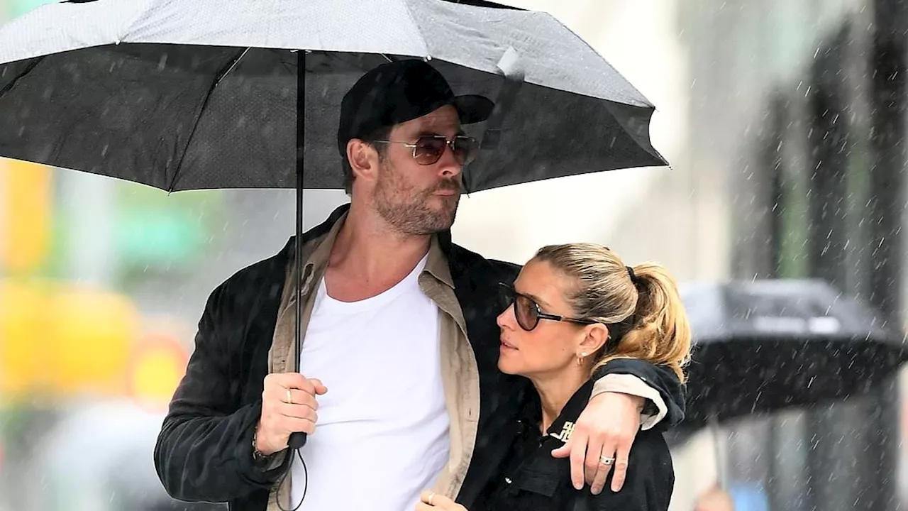 Chris Hemsworth plays the hero as he holds an umbrella to keep wife Elsa Pataky dry on stroll...