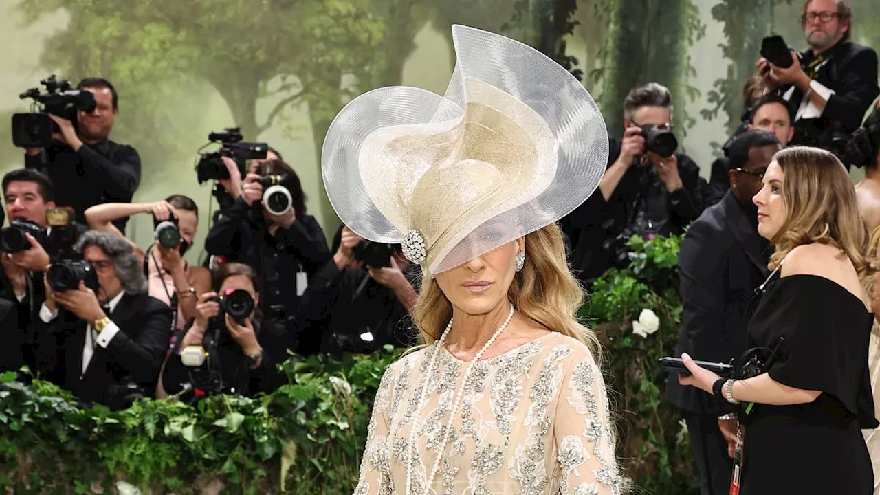 Sarah Jessica Parker channels Carrie Bradshaw with VERY dramatic headpiece and flared gown as she...