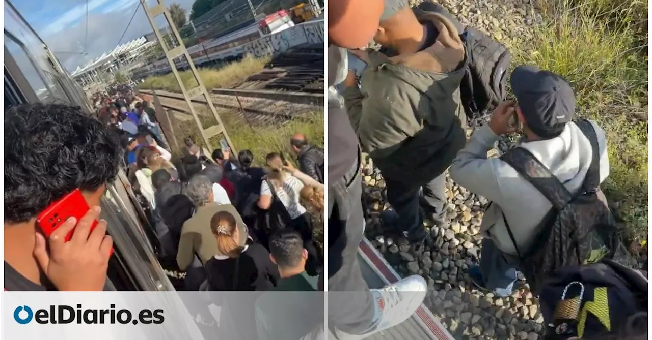 Pasajeros andando por las vías en la entrada a Atocha por una avería en el Cercanías de Madrid