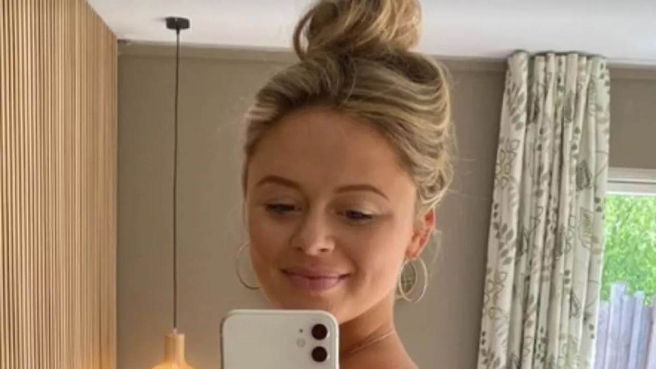 Pregnant Emily Atack proudly cradles her blossoming baby bump in a striking red swimsuit as she...