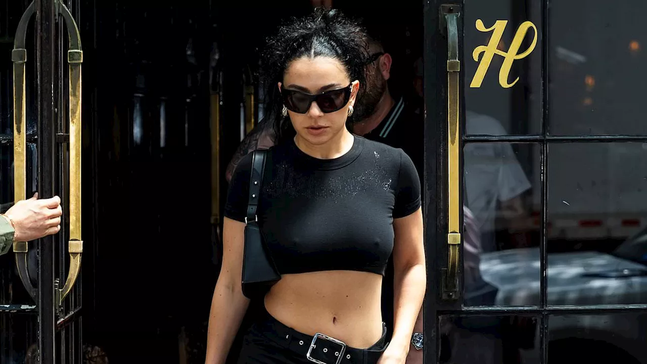 Charli XCX goes braless and flashes her abs in a black crop top as she steps out in New York City...