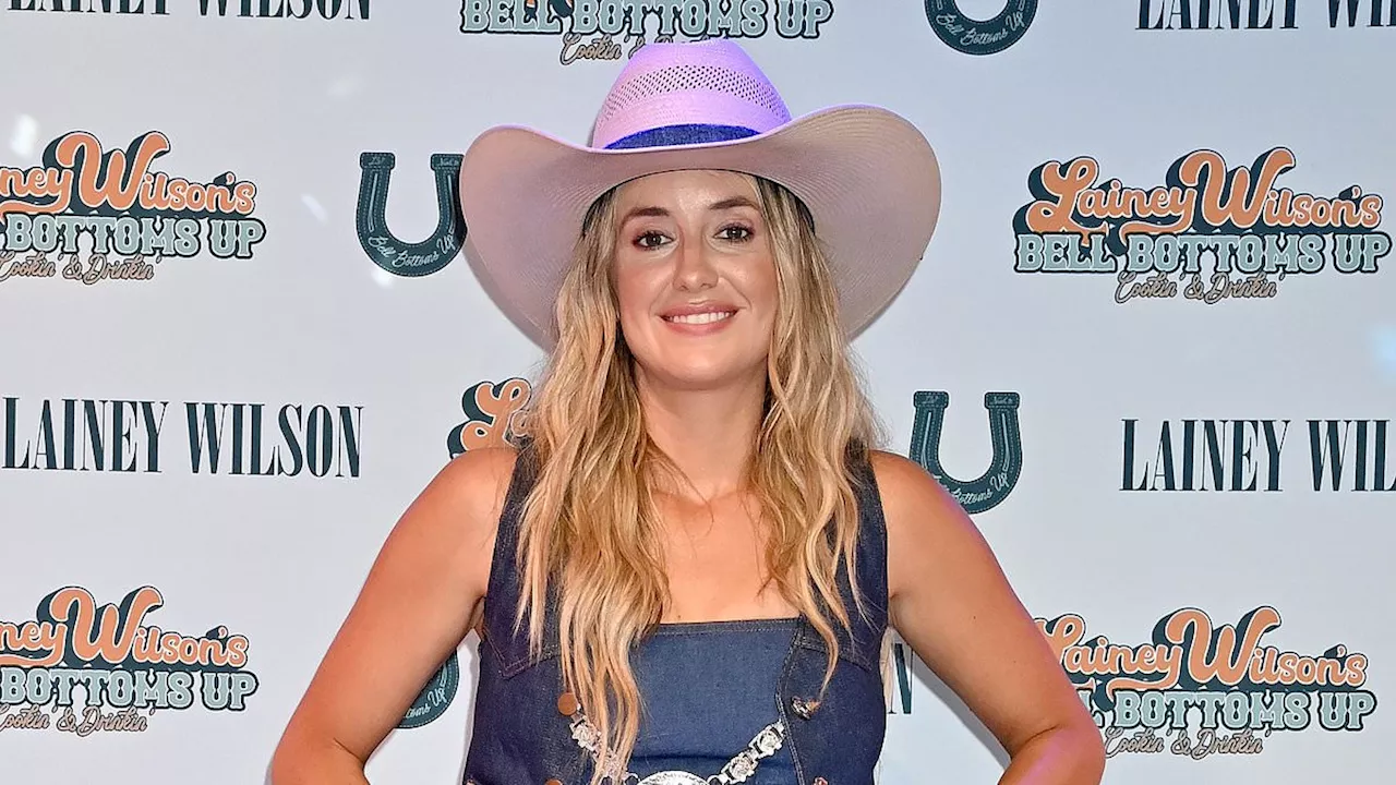 Lainey Wilson shows off her taut tummy in a denim vest and crop top during CMA Music Festival in...