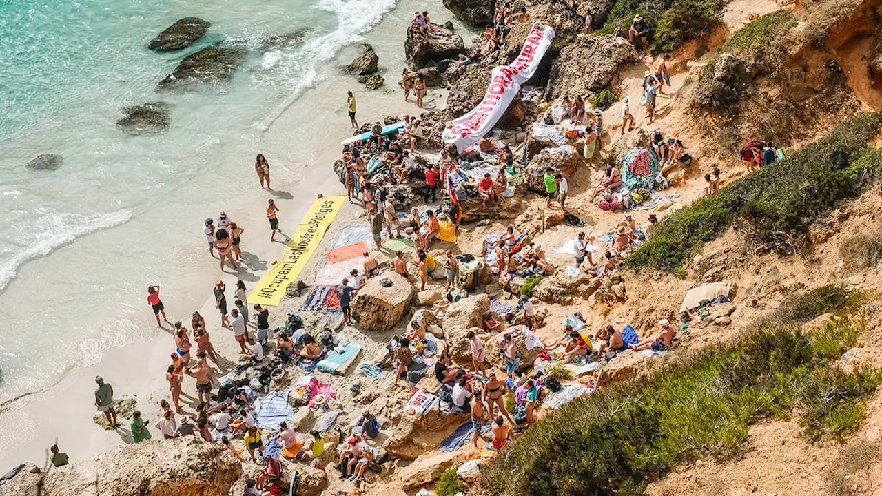 Majorcan locals wearing anti-tourism t-shirts block idyllic cove