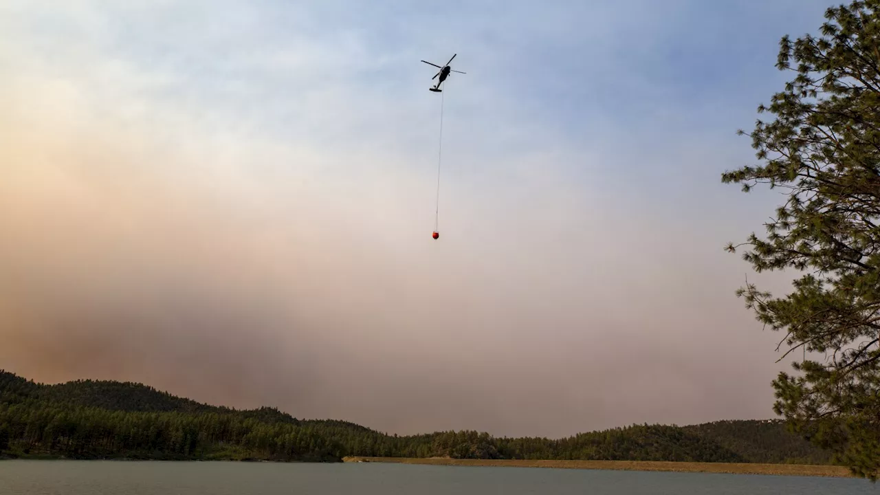 Cooler temps and rain could help corral blazes that forced thousands to fee New Mexico village