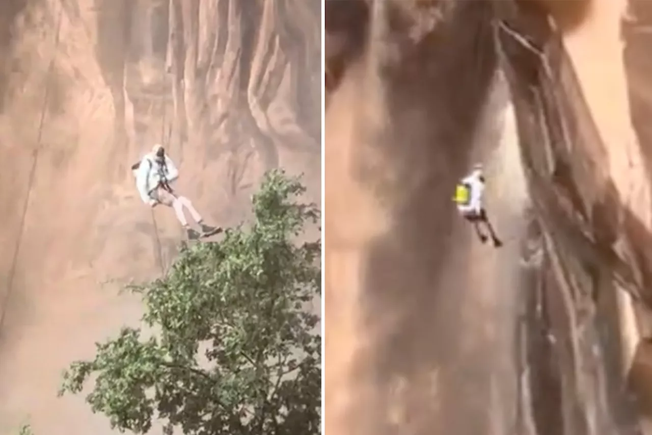 Climber coolly rappels down cliff next to raging muddy waterfall after 'once-in-150-years' storm, dramatic video shows