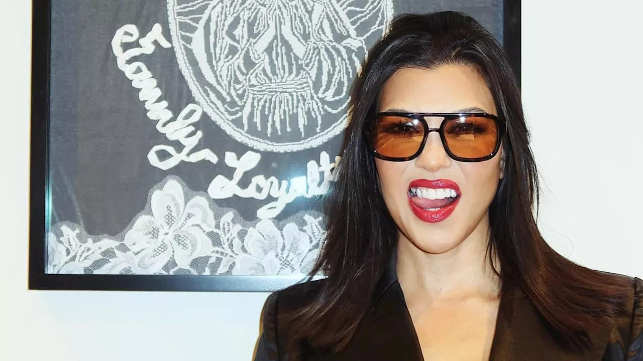 Kourtney Kardashian playfully sticks out her tongue as she shows off her punk rock style in sultry...