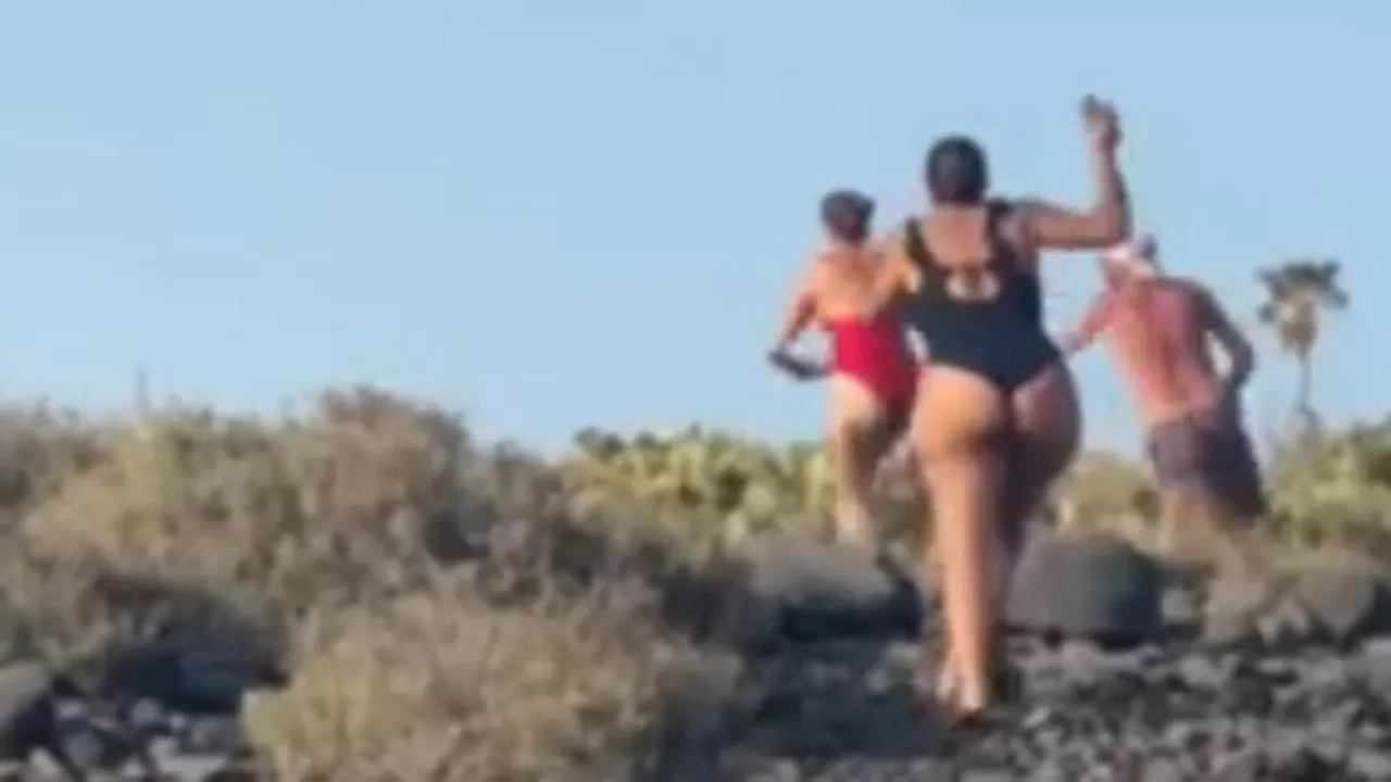 Shocking moment men hurl rocks at each other on Tenerife beach while screaming women desperately try...