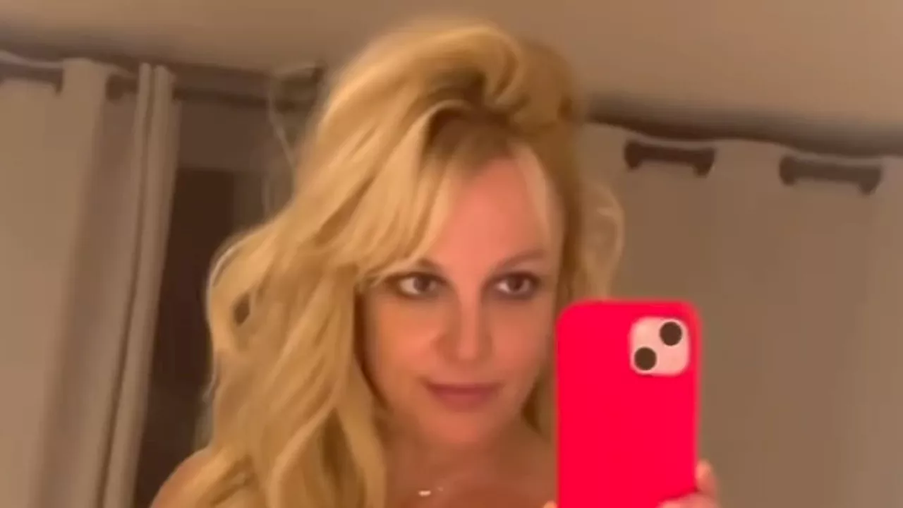 Britney Spears models plunging mesh minidress before changing into sexy off-the-shoulder yellow...