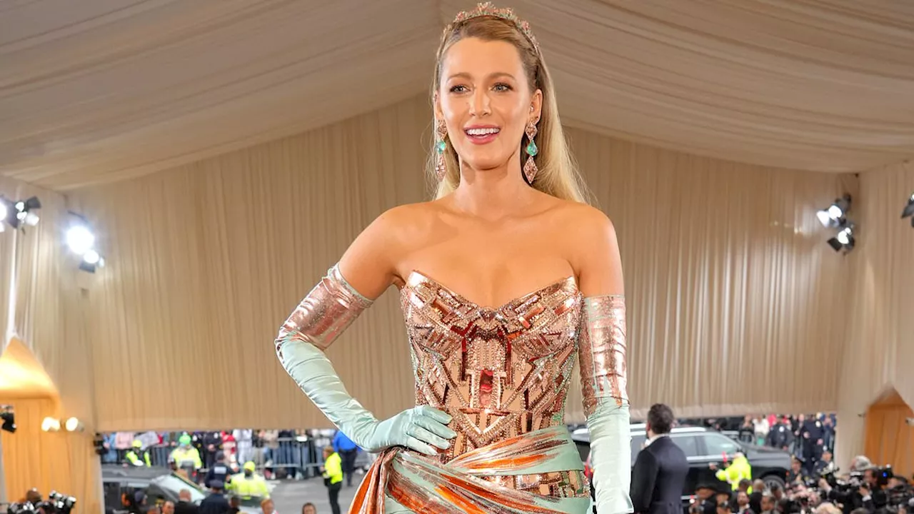 Blake Lively almost spills out of her floral-print bra top as she adds a very full tulle skirt while...