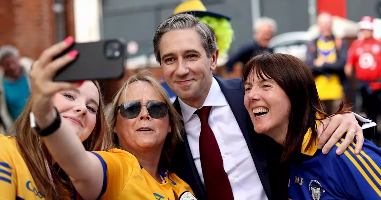 Taoiseach Simon Harris poses for photos with Cork and Clare fans ahead of final