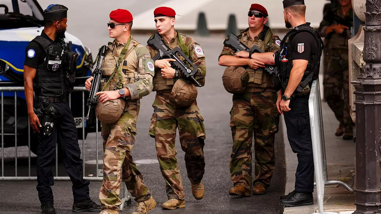 Olympics ring of steel: Armed guards patrol Paris streets and metal barriers go up along the Seine...