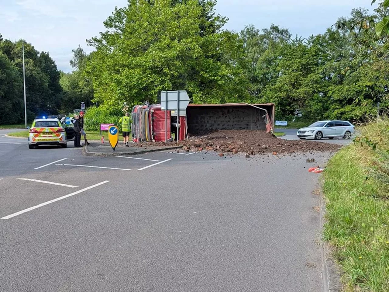 Road blocked after lorry crashes onto its side at roundabout spilling load