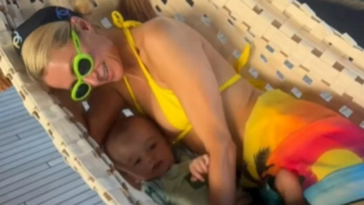 Paris Hilton is every inch the hot mama in a yellow bikini while snuggling with her son Phoenix,...