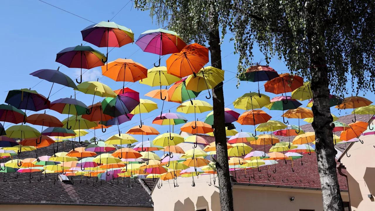 Bunte Regenschirme schenken Freude und Schatten im Amtshof