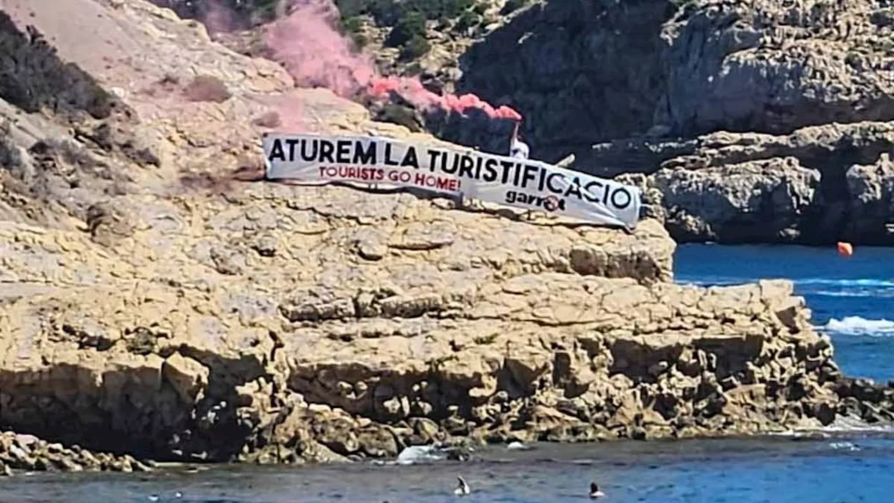 Spain's war on holidaymakers strikes again as furious protesters unfurl poster and set off flares...