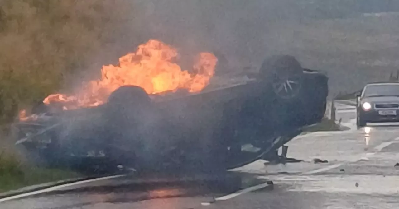 Emergency crews rush to Dunbartonshire road as car on roof engulfed in flames