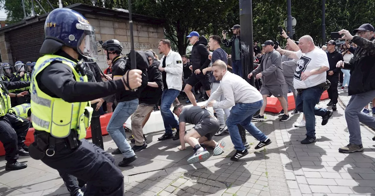 Far-right clash with riot cops in Manchester as metal fences hurled at officers