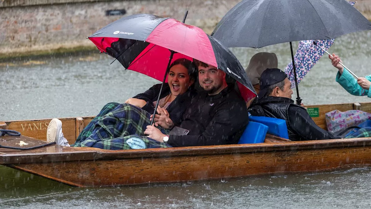 It was worth a punt! Cambridge pleasure boaters huddle beneath brollies and blankets as stormy...