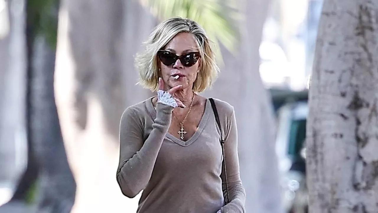 Melanie Griffith puffs on a cigarette wearing lace fingerless gloves as she steps out in stylish...