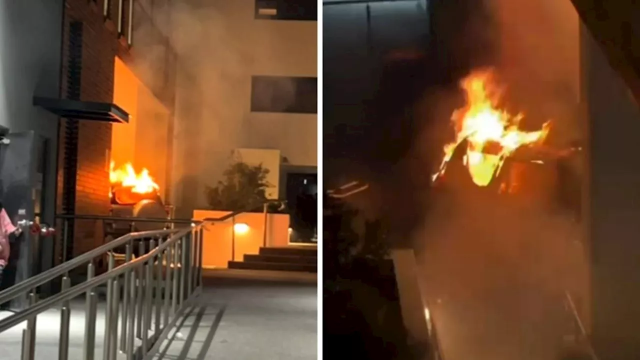 Hundreds of people evacuated after allegedly stolen car erupts into flames after crashing into unit block in Sydney