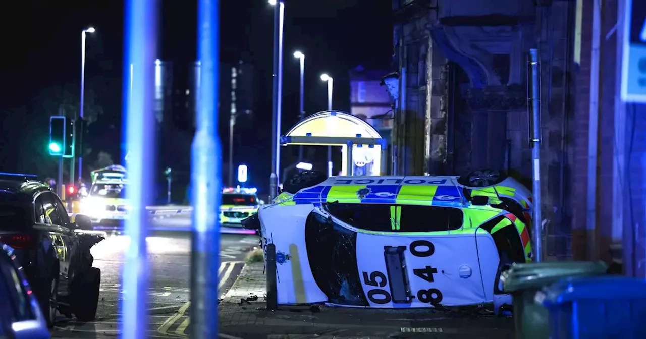 Road closed as police car on its side after crash