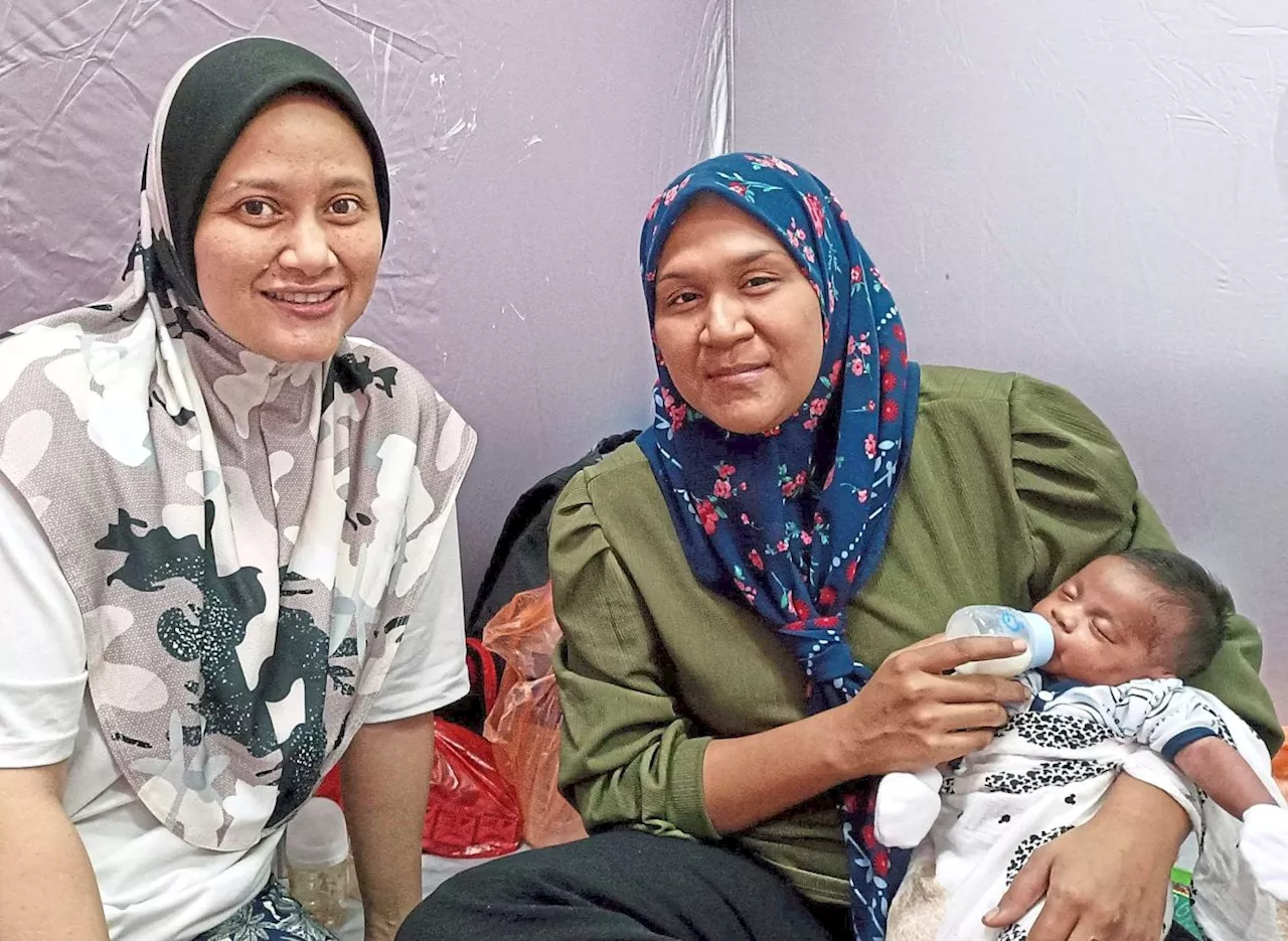 Two mothers lean on each other at relief centre