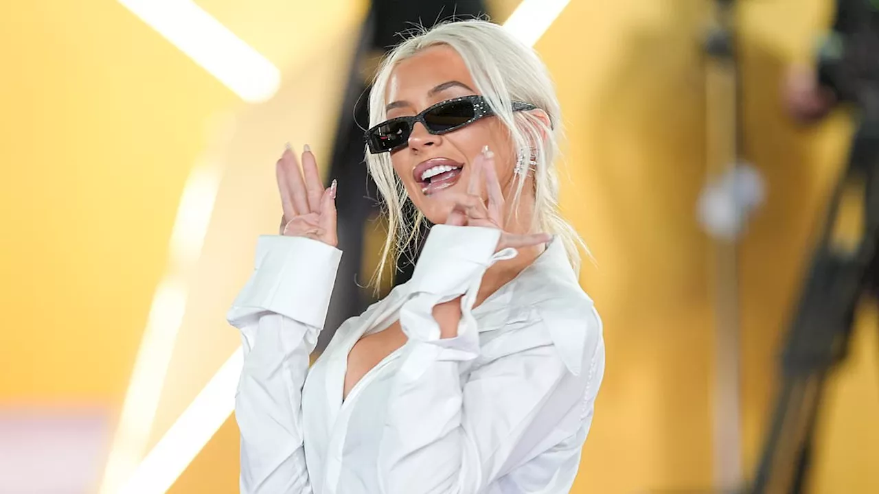 Christina Aguilera continues to show off her dramatic weight loss in a stylish shirt and shimmering...