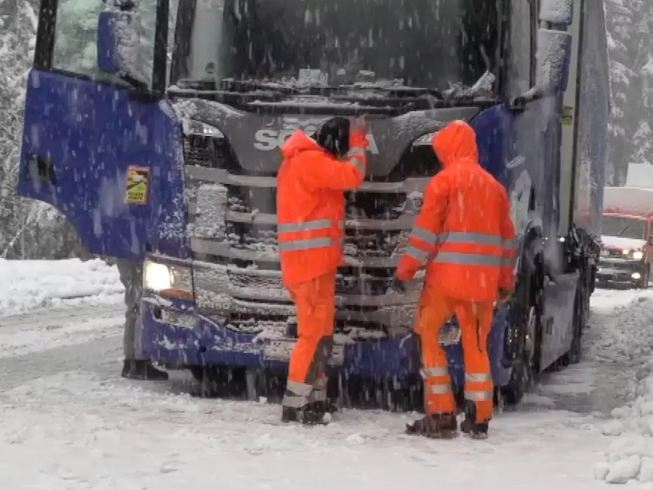 Lkw-Fahrer baut Schneeketten aus Spanngurt