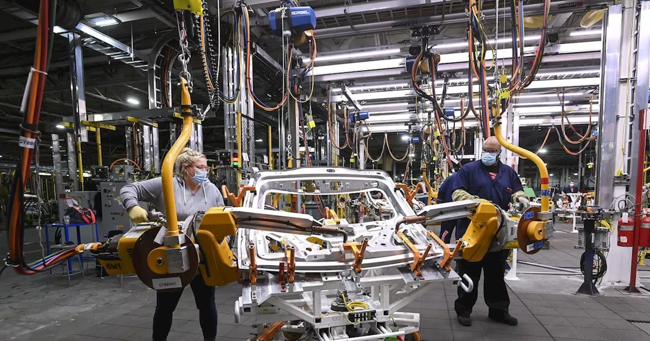 GM workers use human assistance automation to weld vehicle doors