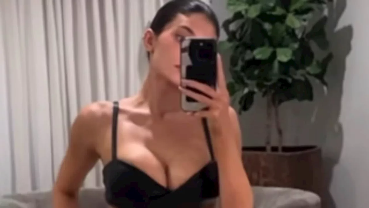 Kylie Jenner pulls down her pleather slacks to show a hint of her butt as she models a low-cut bra...