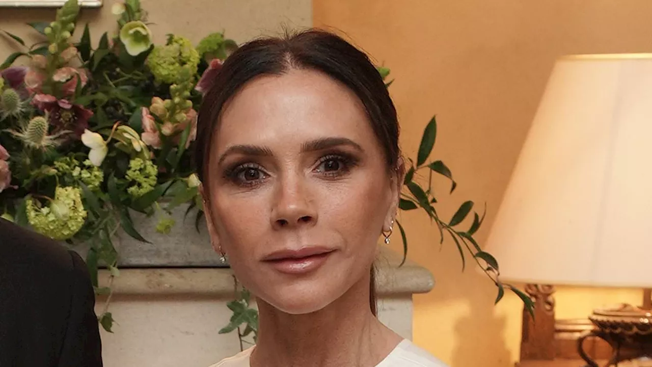 Victoria Beckham dazzles in a £1,000 elegant silk white gown from her own collection as she joins...